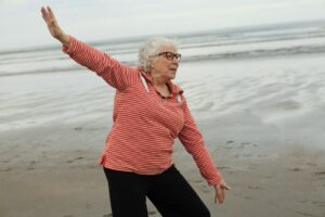 Woman practices tai chi on the beach.